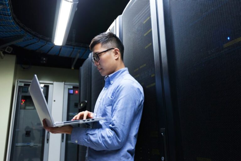 Young IT engineer inspecting data center servers - Implementation Services